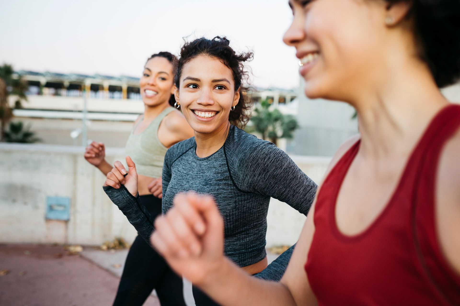 A group of women are running together and smiling.