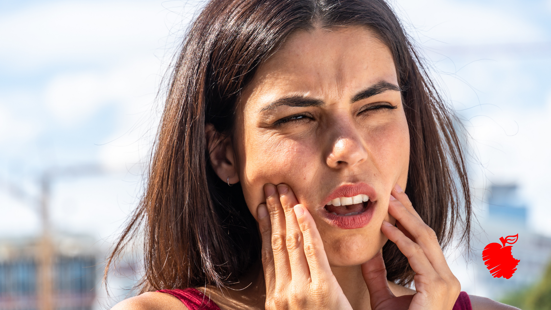 A woman is holding her face in pain because of a toothache.