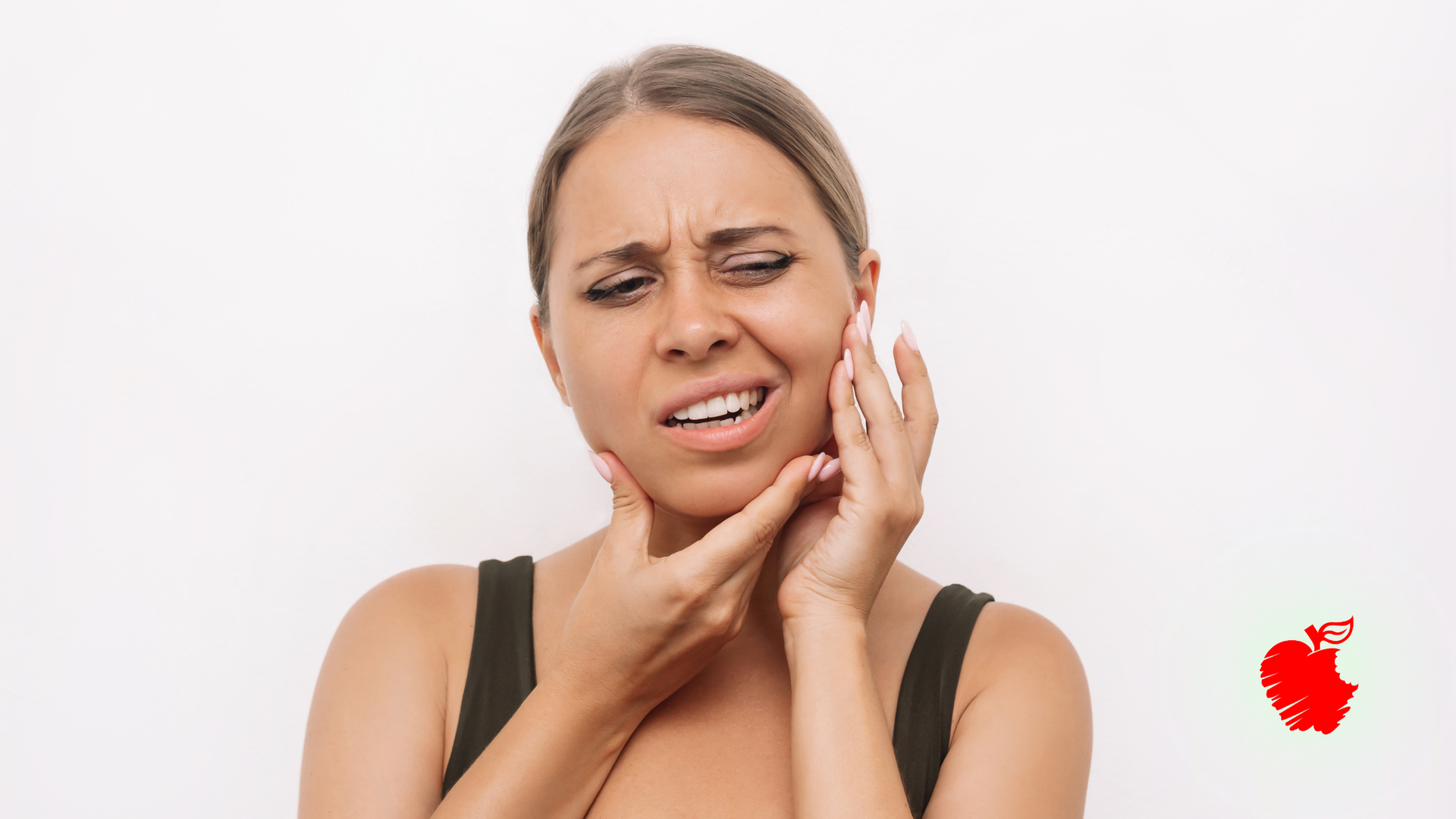 Woman holding her cheek with a pained expression against a white background