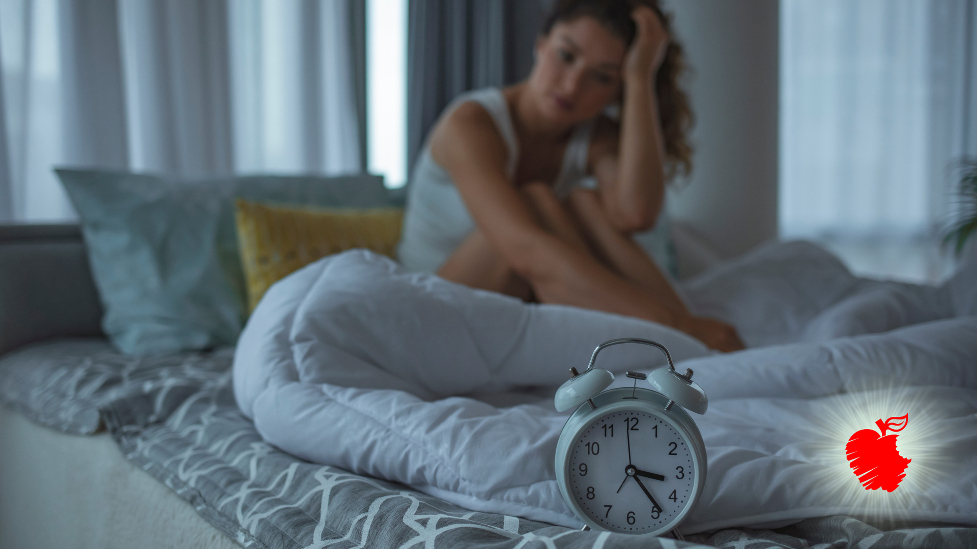 Person sitting on a bed in a dim bedroom, looking pensive beside an alarm clock in the foreground.