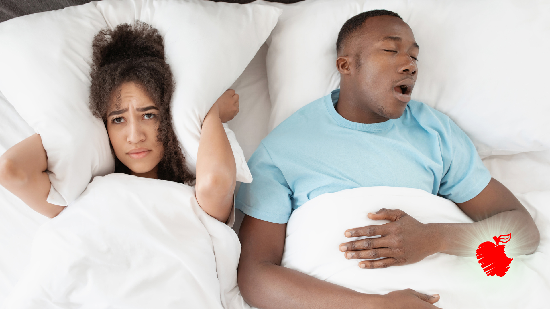 Couple in bed, one upset and covering ears while the other sleeps with mouth open and a red heart icon near him