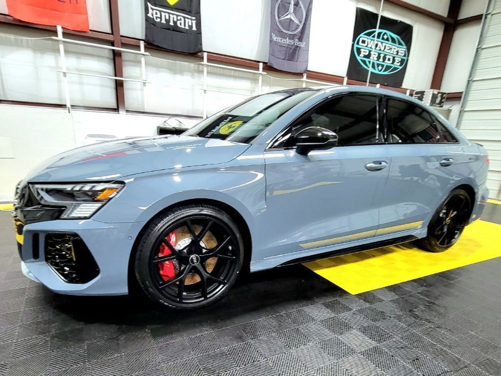 Gray Audi sedan with black wheels and red brake calipers, parked inside a garage.