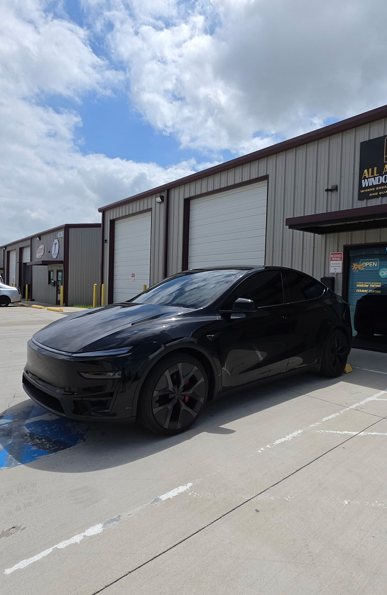 Gloved hand polishing a glossy black car with a blue applicator pad
