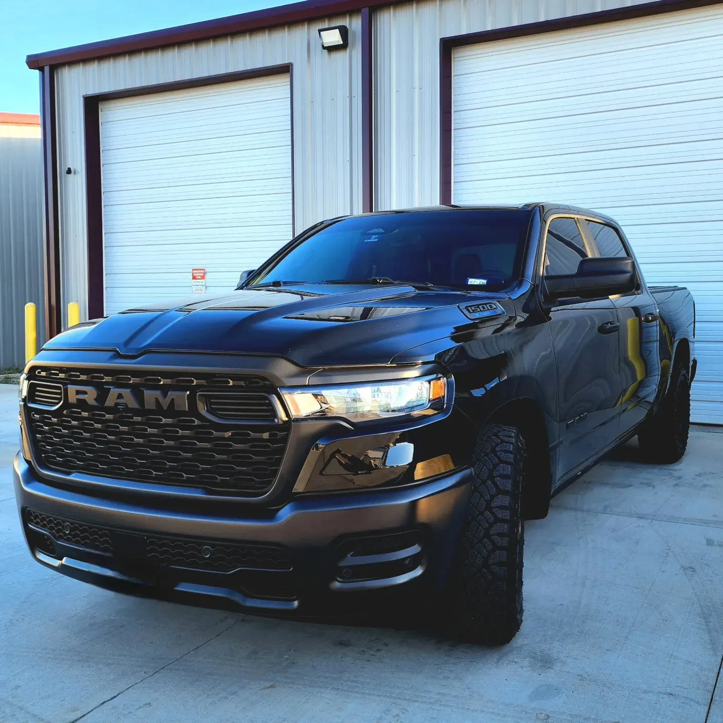 Black RAM pickup truck parked in front of a garage building
