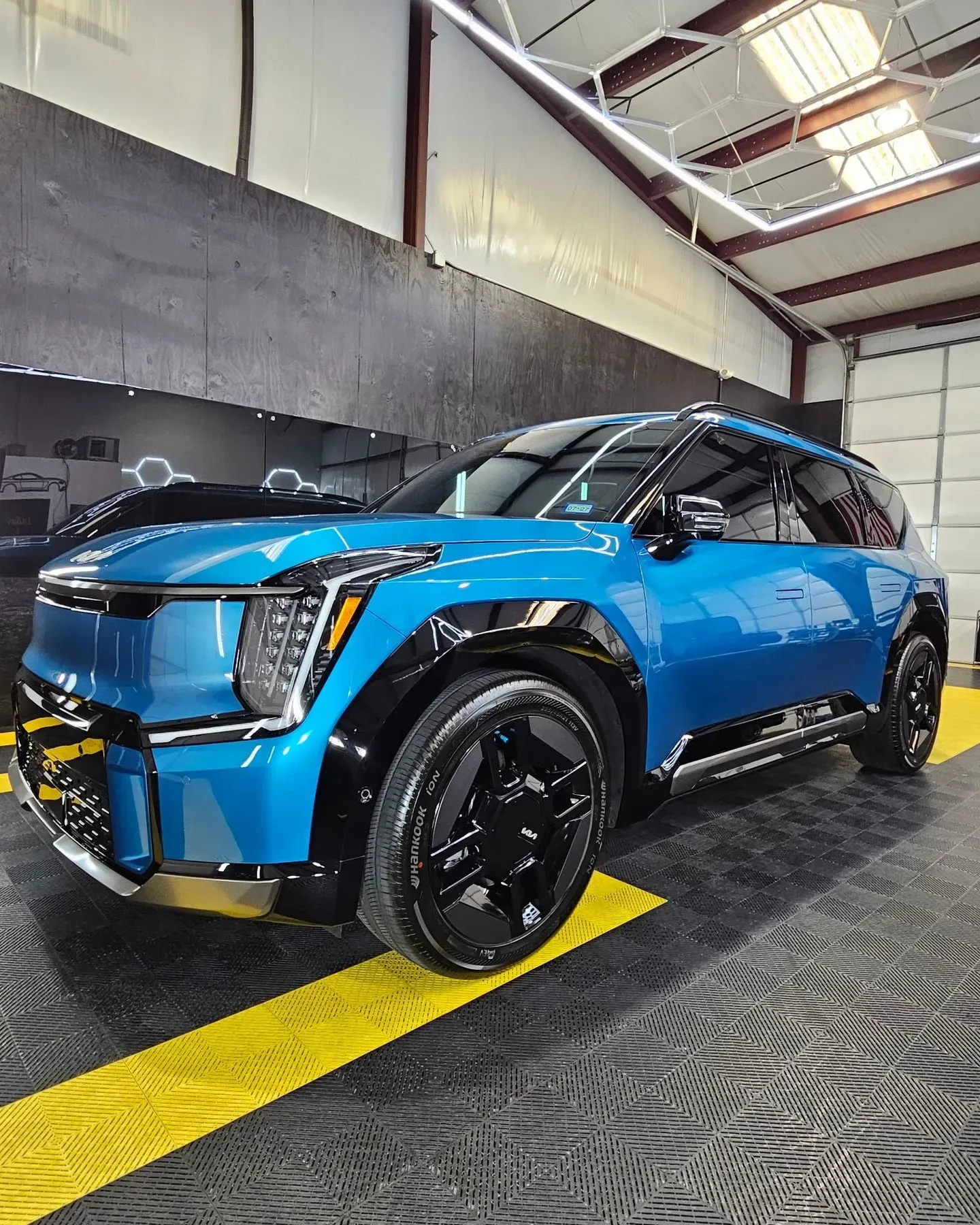 Blue SUV with black accents displayed indoors in a showroom or garage.
