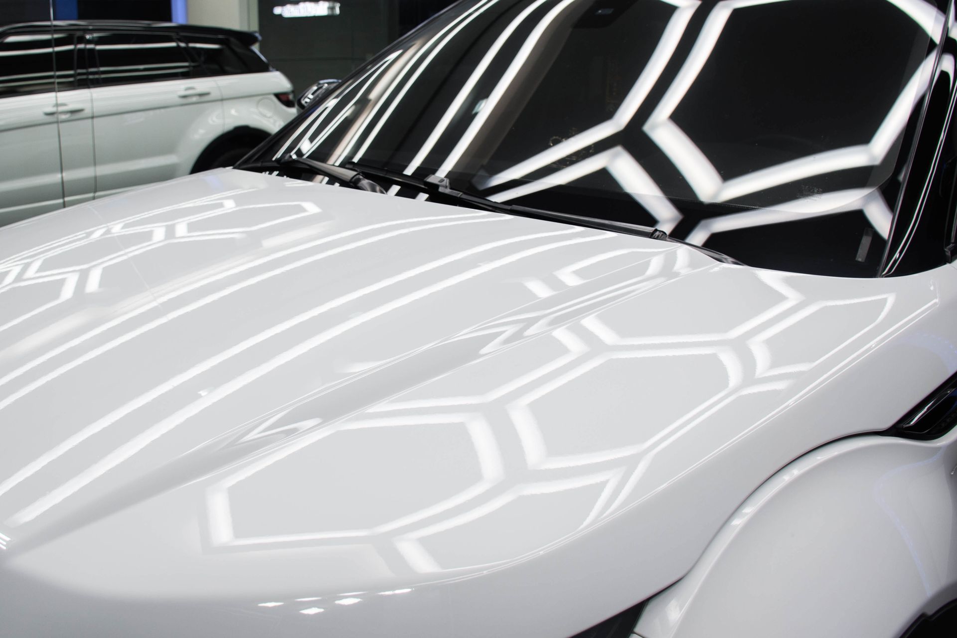 White car hood with reflective geometric light patterns, parked indoors