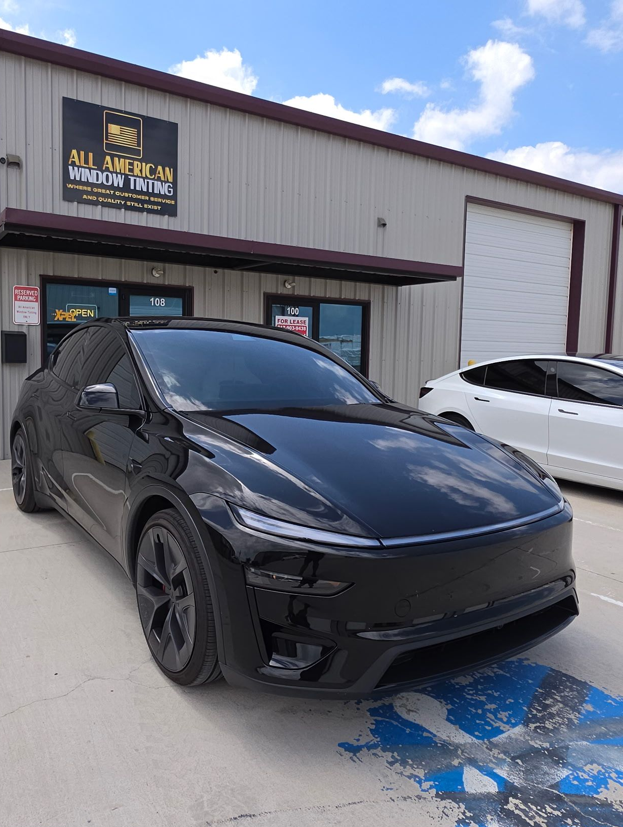 Black sports car parked outside a metal building on a sunny day