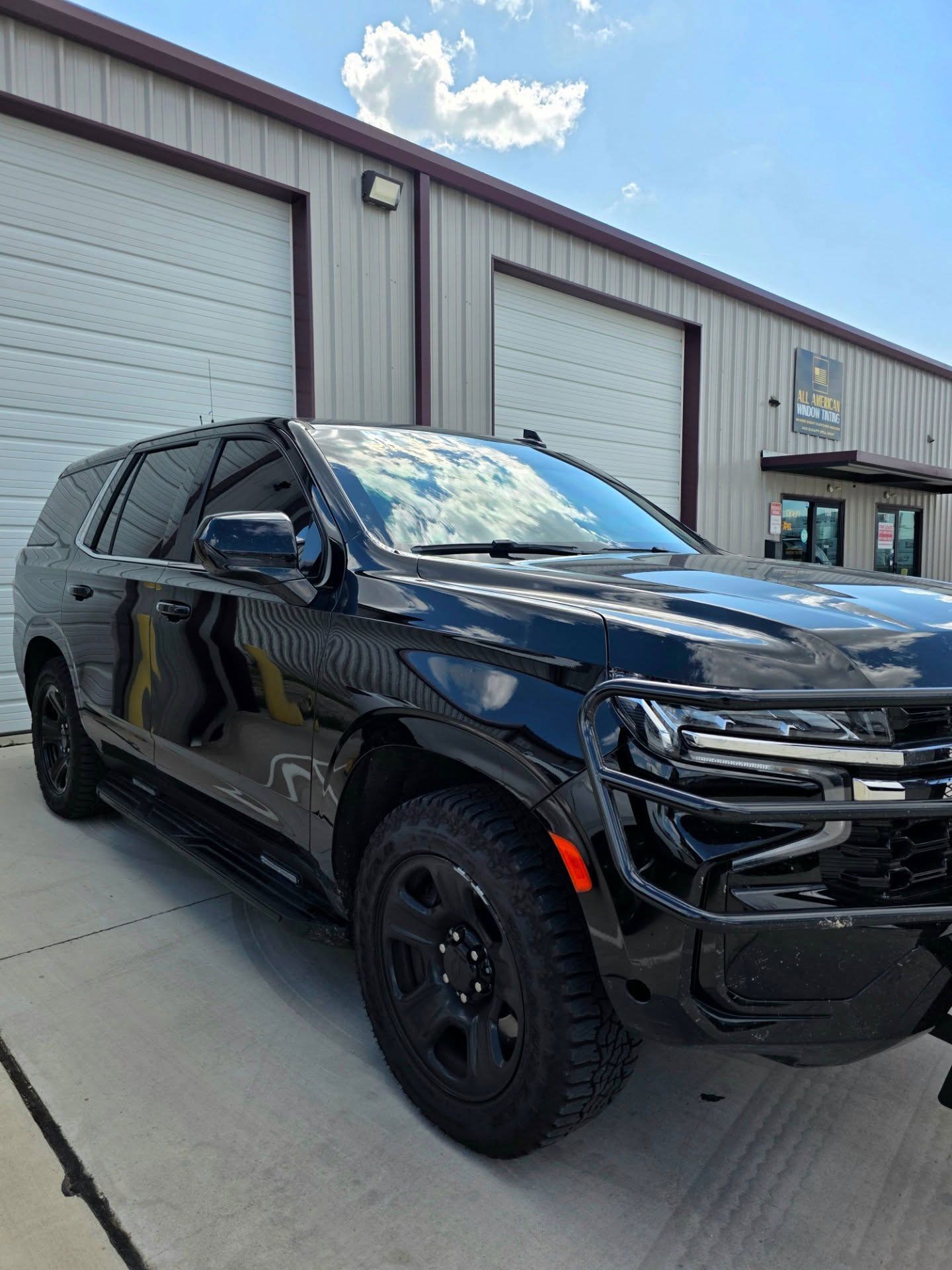 Black SUV parked outside an industrial building on a sunny day