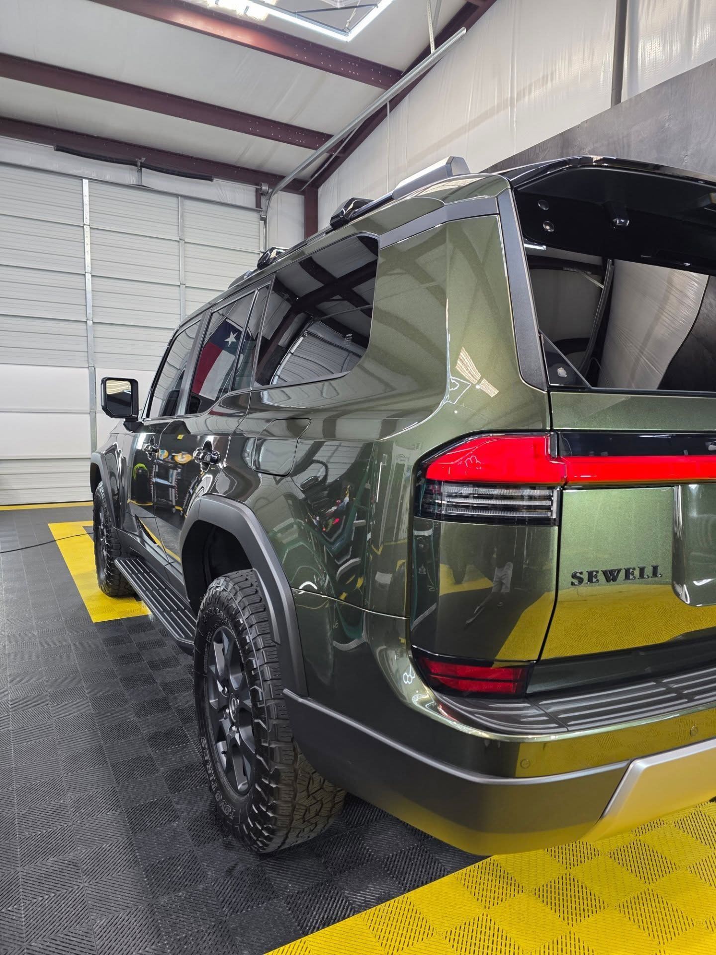 Green SUV parked in a garage, rear three-quarter view with taillights visible.