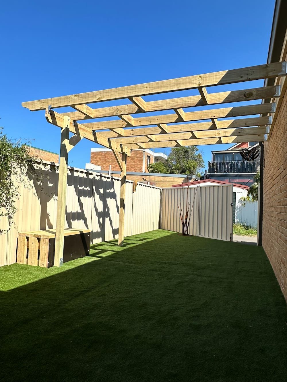 A Wooden Pergola Is Sitting On Top Of A Lush Green Lawn — Newcastle Patio Covers In Port Stephens, NSW