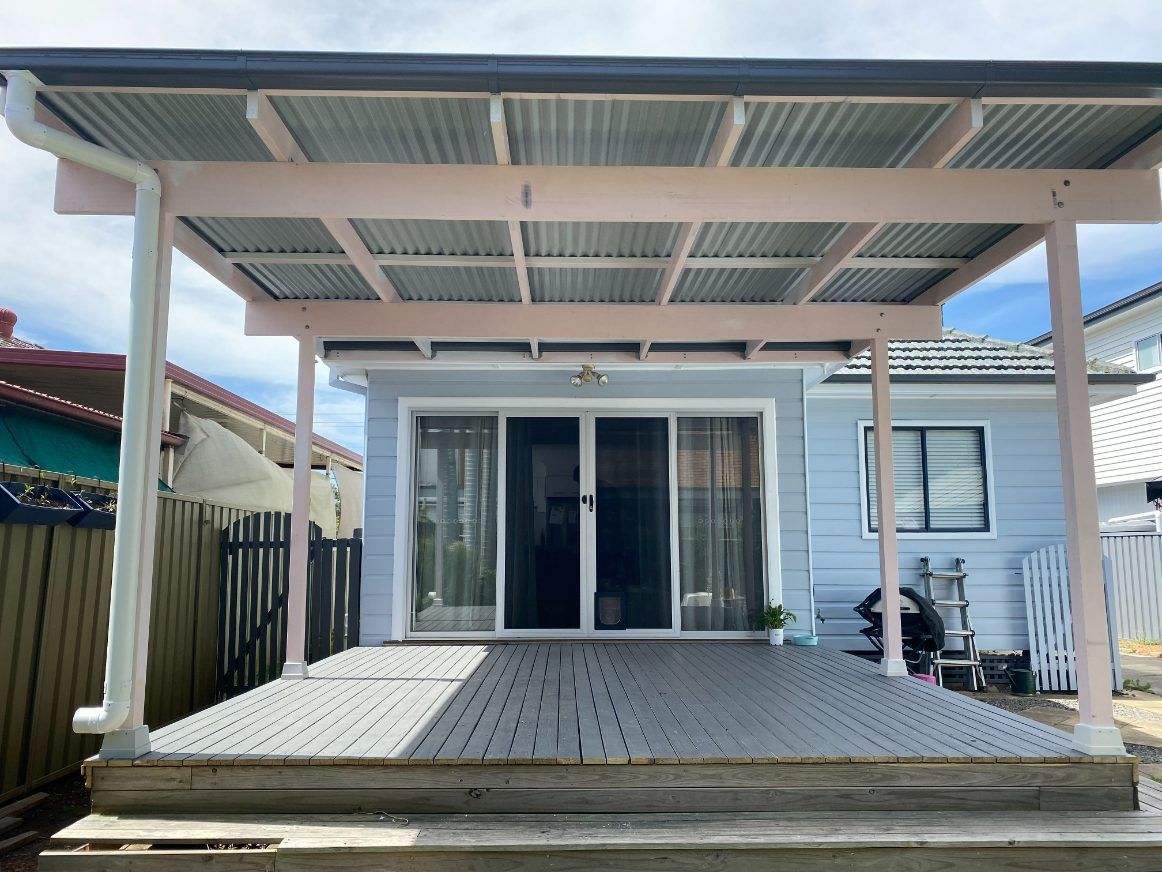 A Patio Cover With A Blue Roof And Wooden Beams — Newcastle Patio Covers In Wallsend, NSW