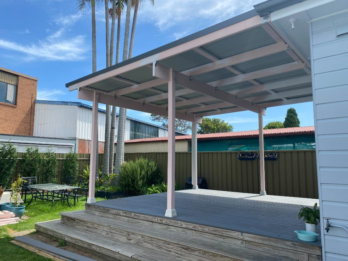 A Patio Cover With A Blue Roof And Wooden Beams — Newcastle Patio Covers In Wallsend, NSW
