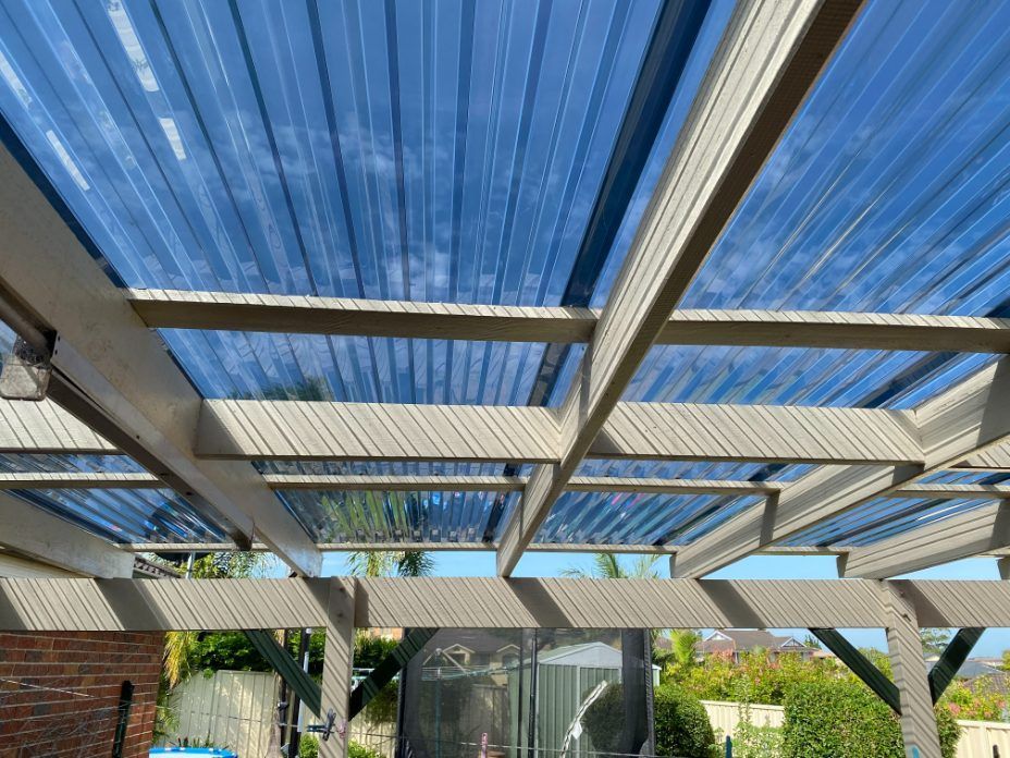 A Pergola With A Blue Roof And Wooden Beams — Newcastle Patio Covers In Wallsend, NSW