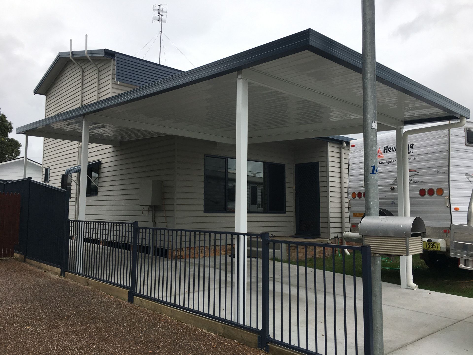 A White Colourbond Verandah With A Black Metal Fence Beside It— Newcastle Patio Covers In Wallsend, NSW