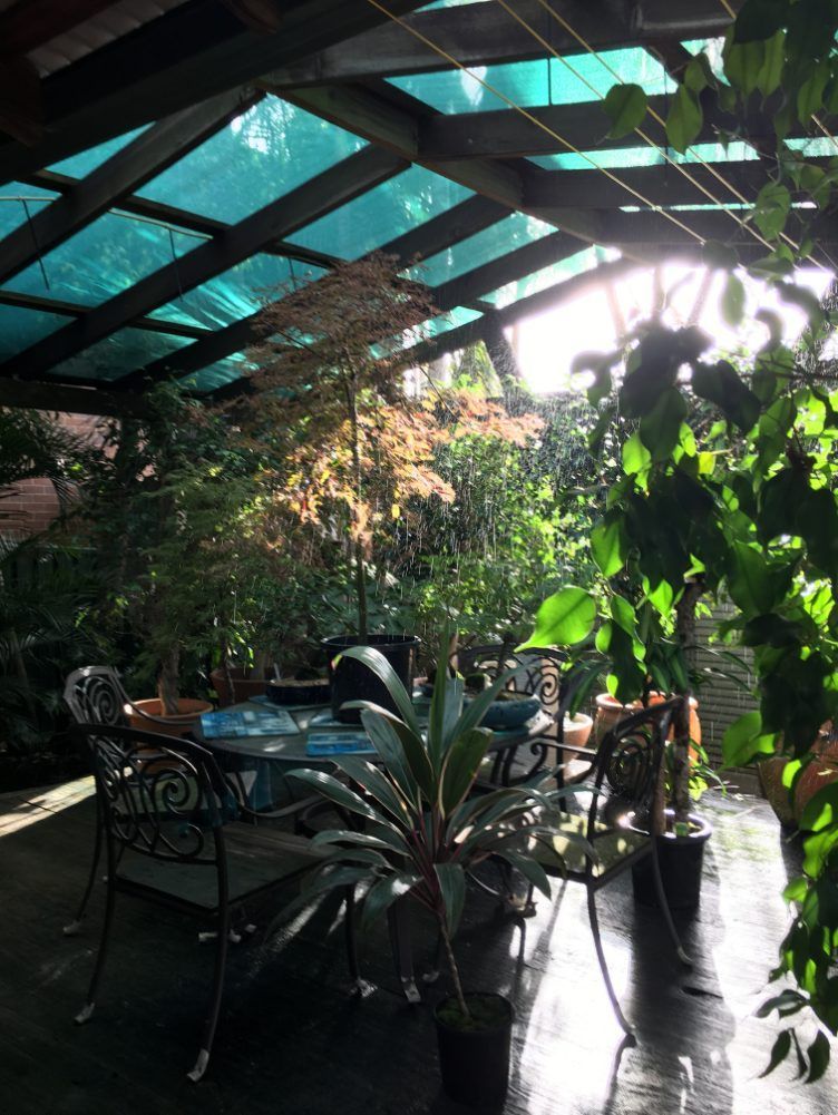A Patio With A Table And Chairs Under A Glass Roof — Newcastle Patio Covers In Wallsend, NSW