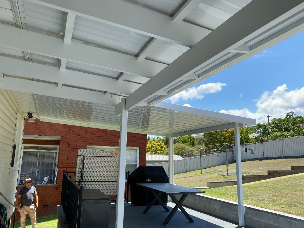 A Man Is Standing Under An Awnings — Newcastle Patio Covers In Wallsend, NSW