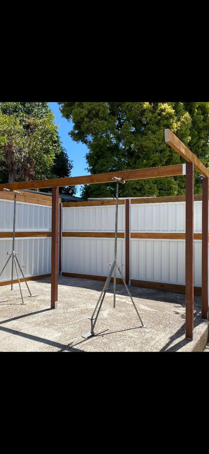 A Wooden Structure Is Being Built In Front Of A White Fence — Newcastle Patio Covers In Wallsend, NSW