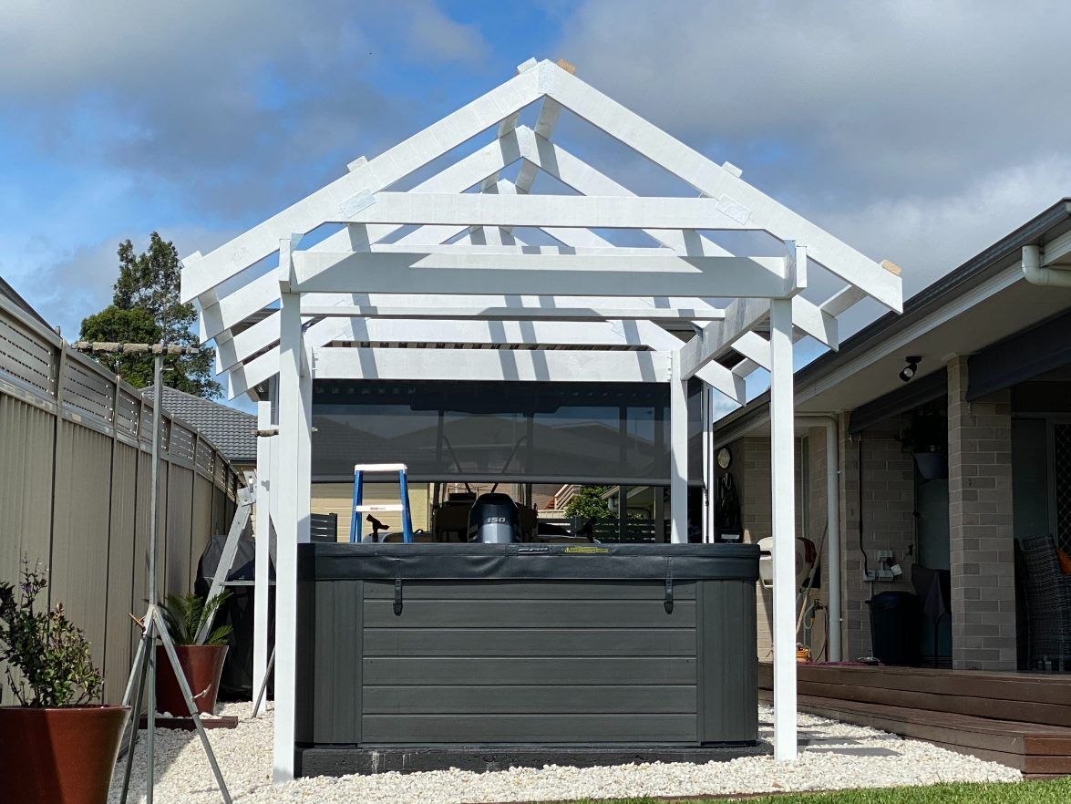 A Black Hot Tub Is Under A White Pergola In A Backyard — Newcastle Patio Covers In Wallsend, NSW