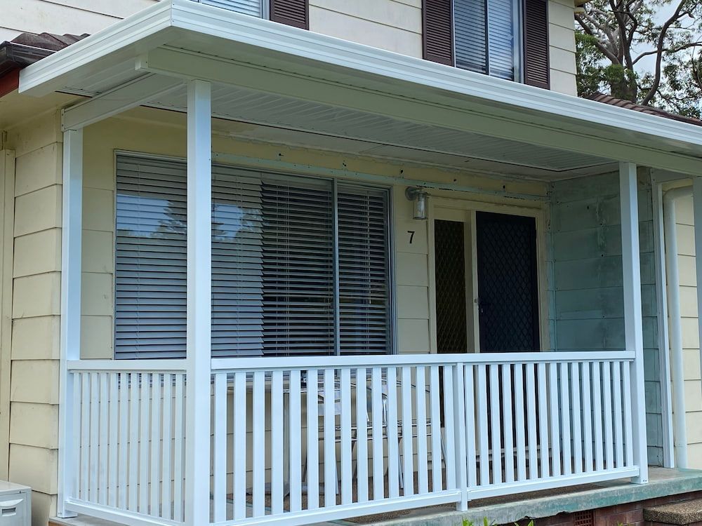 A House With A Verandah And White Wooden Railing Underneath— Newcastle Patio Covers In Wallsend, NSW
