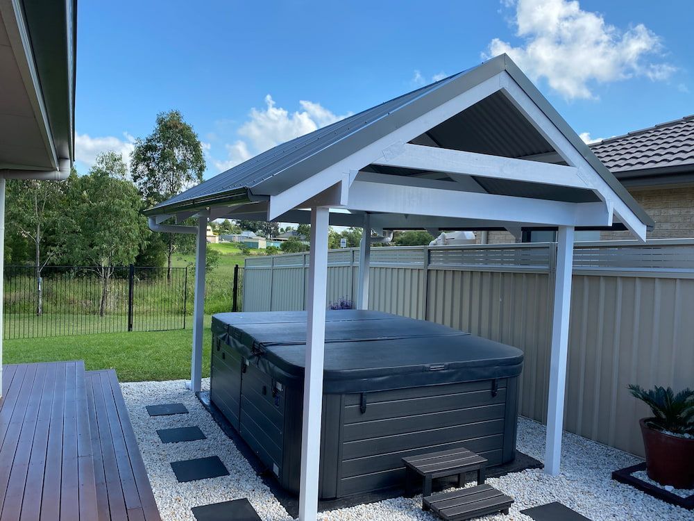 A Hot Tub Is Under A Gazebo In The Backyard Of A House — Newcastle Patio Covers In Wallsend, NSW