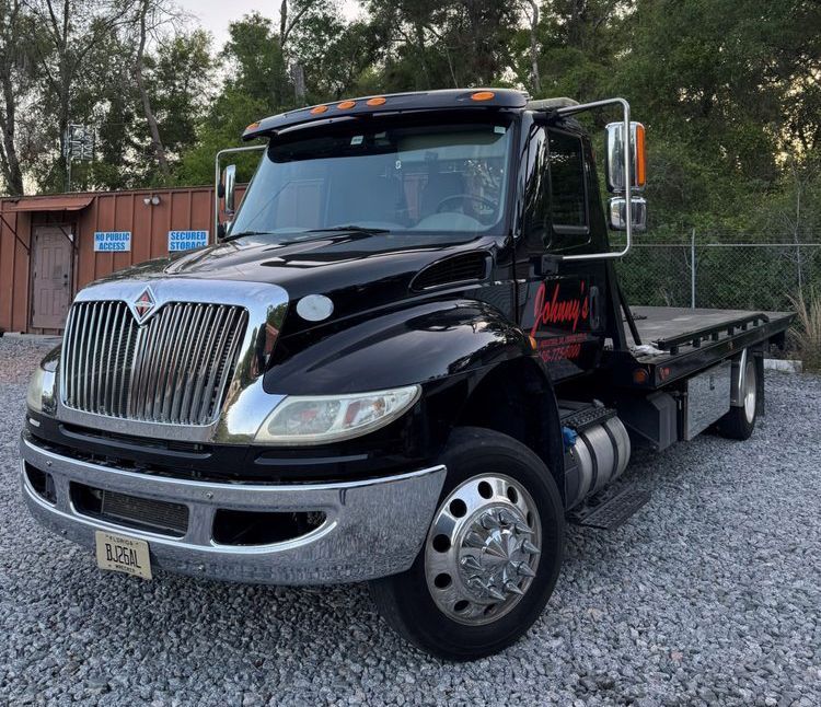 Black tow truck with chrome accents parked outside.