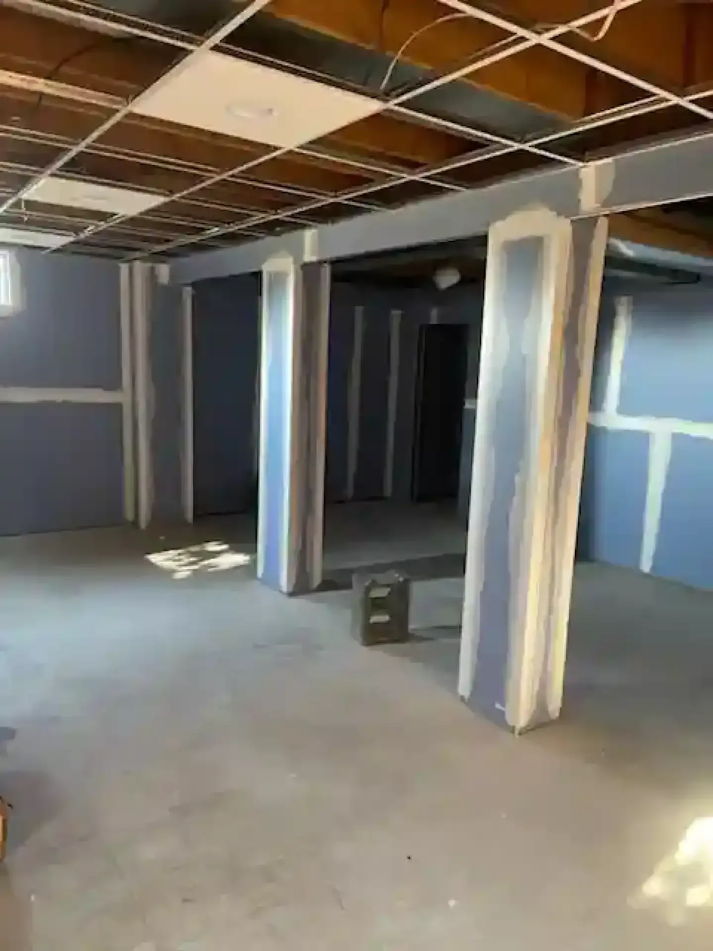 Empty unfinished room with drywall, exposed ceiling framing, and a concrete floor.