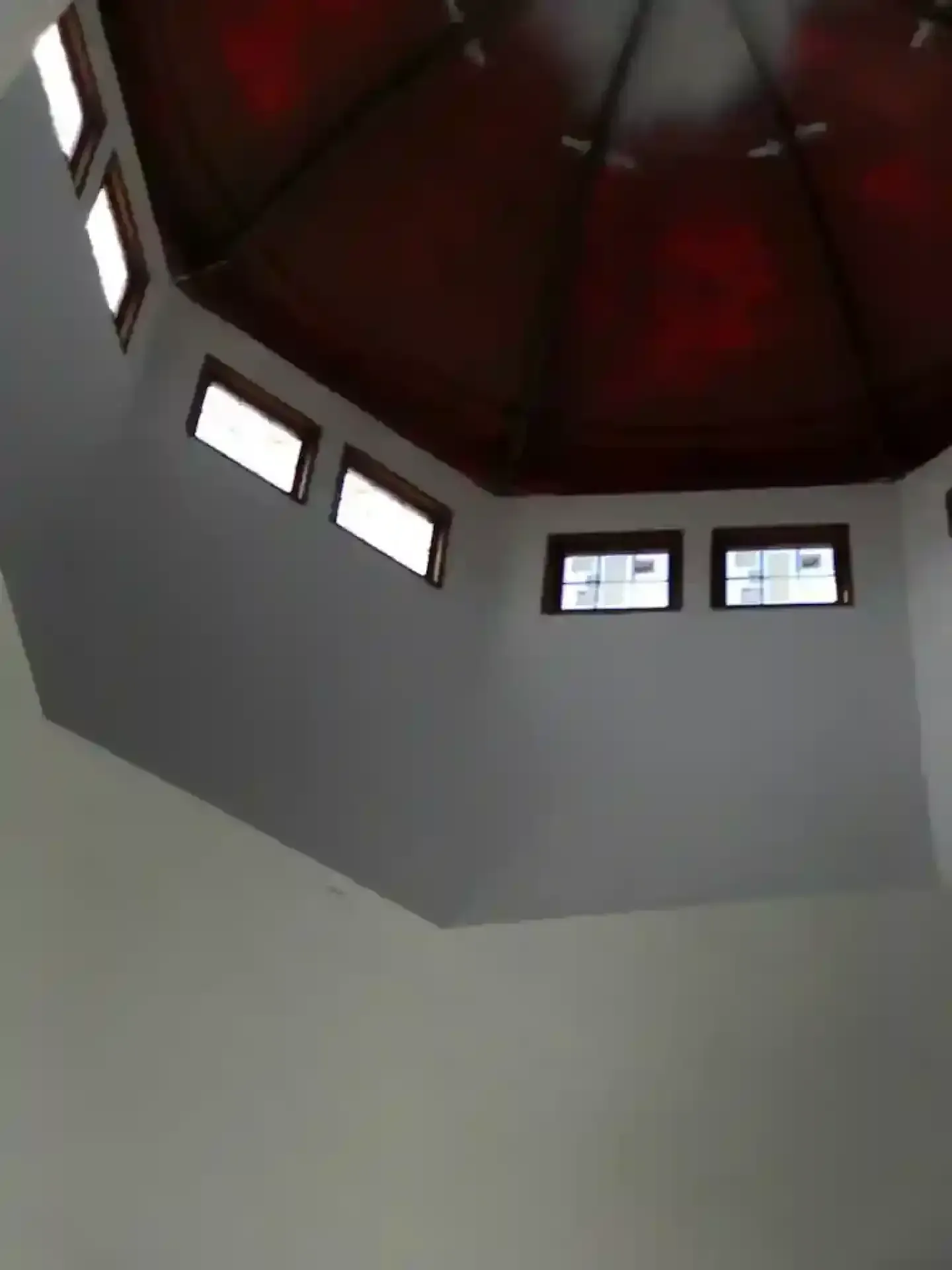 Interior ceiling with dark red dome and small rectangular windows against white walls