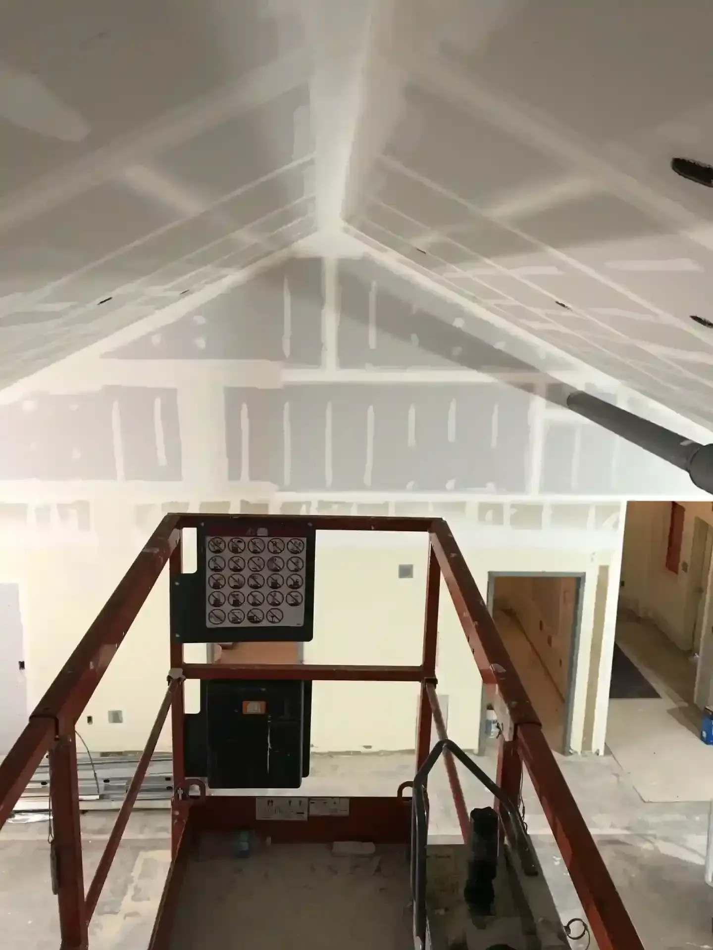 Attic with drywall, exposed beams, and a small scaffold beneath the sloped ceiling