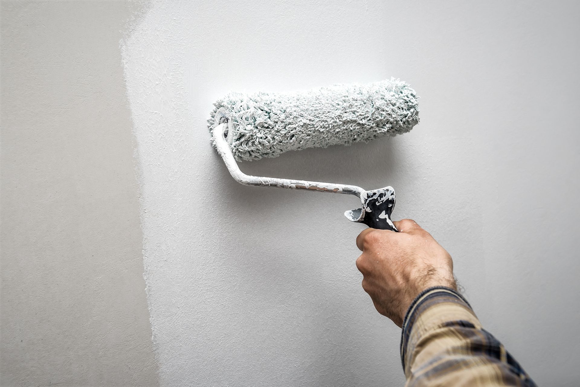 Hand painting a white wall with a paint roller