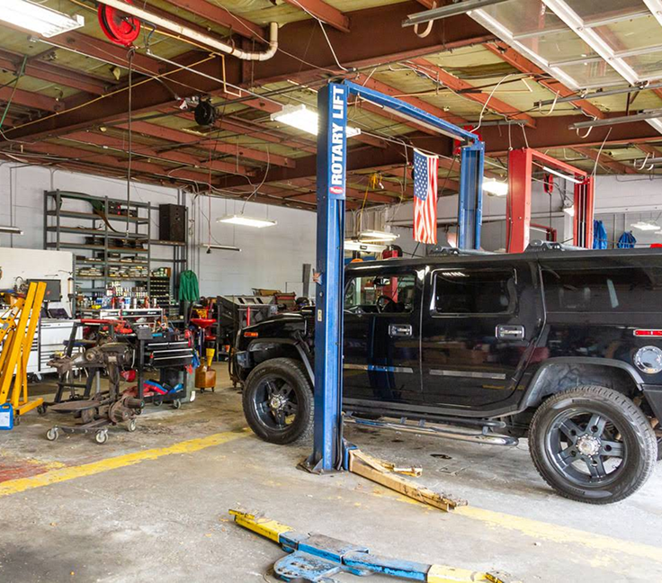 Auto repair shop with a black SUV on a lift and tools cluttered around the garage. | Charlie's Car Care