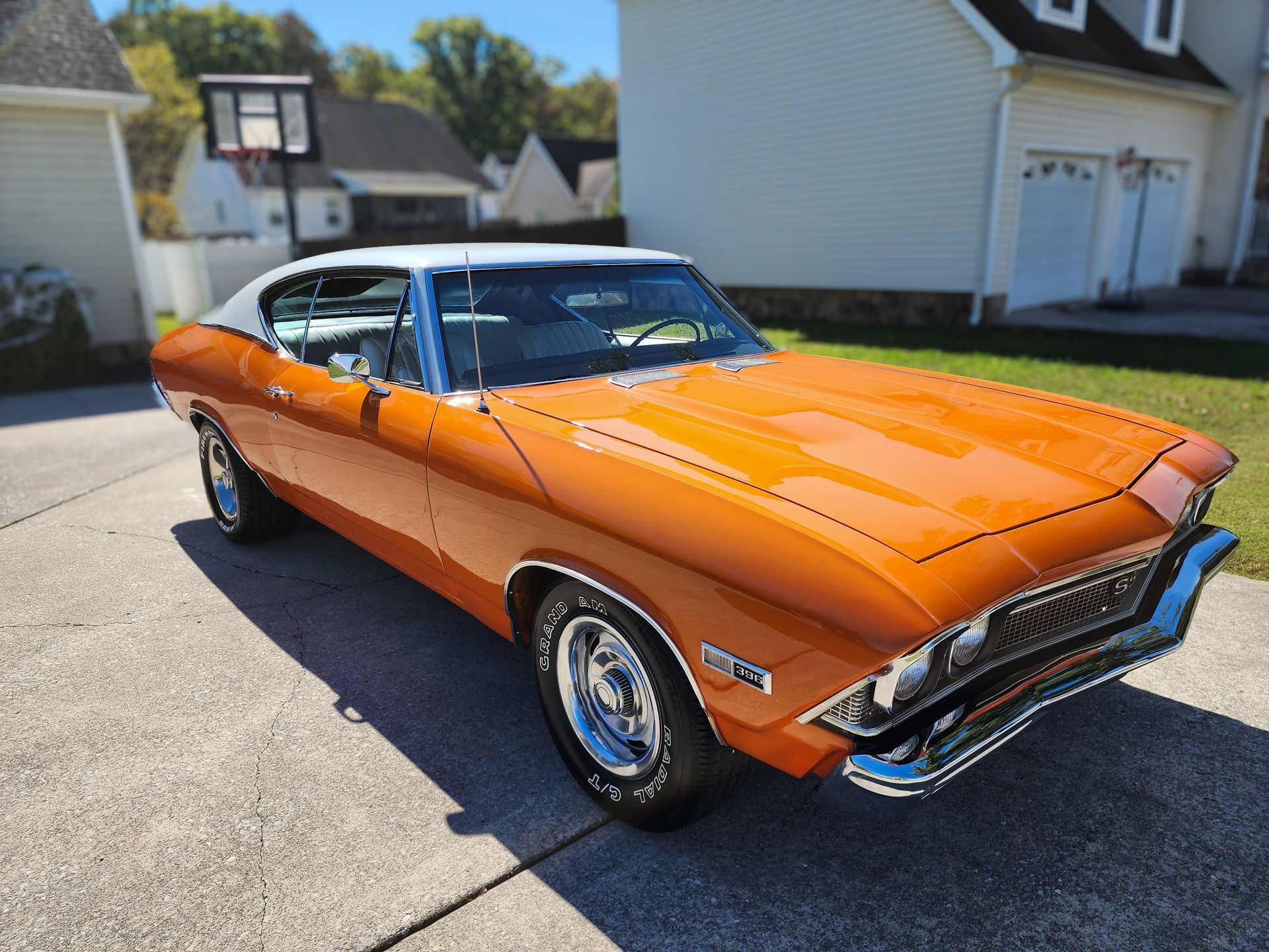 Orange and White Chevy Malibu reflecting the sun off its glossy paint.