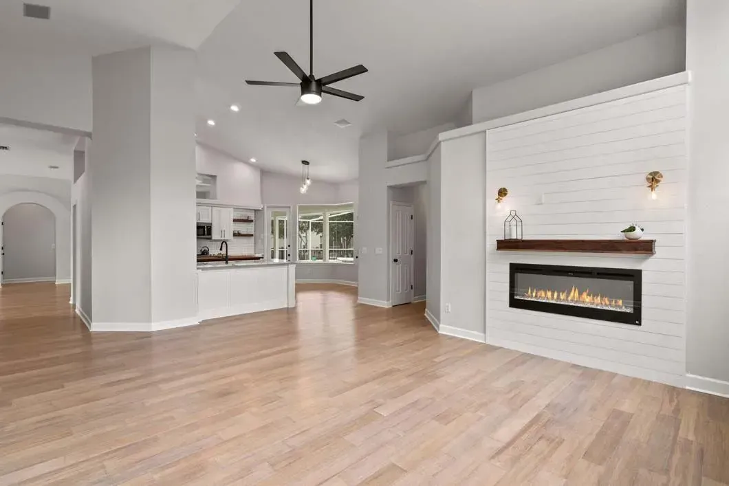 A living room with a fireplace and a ceiling fan.
