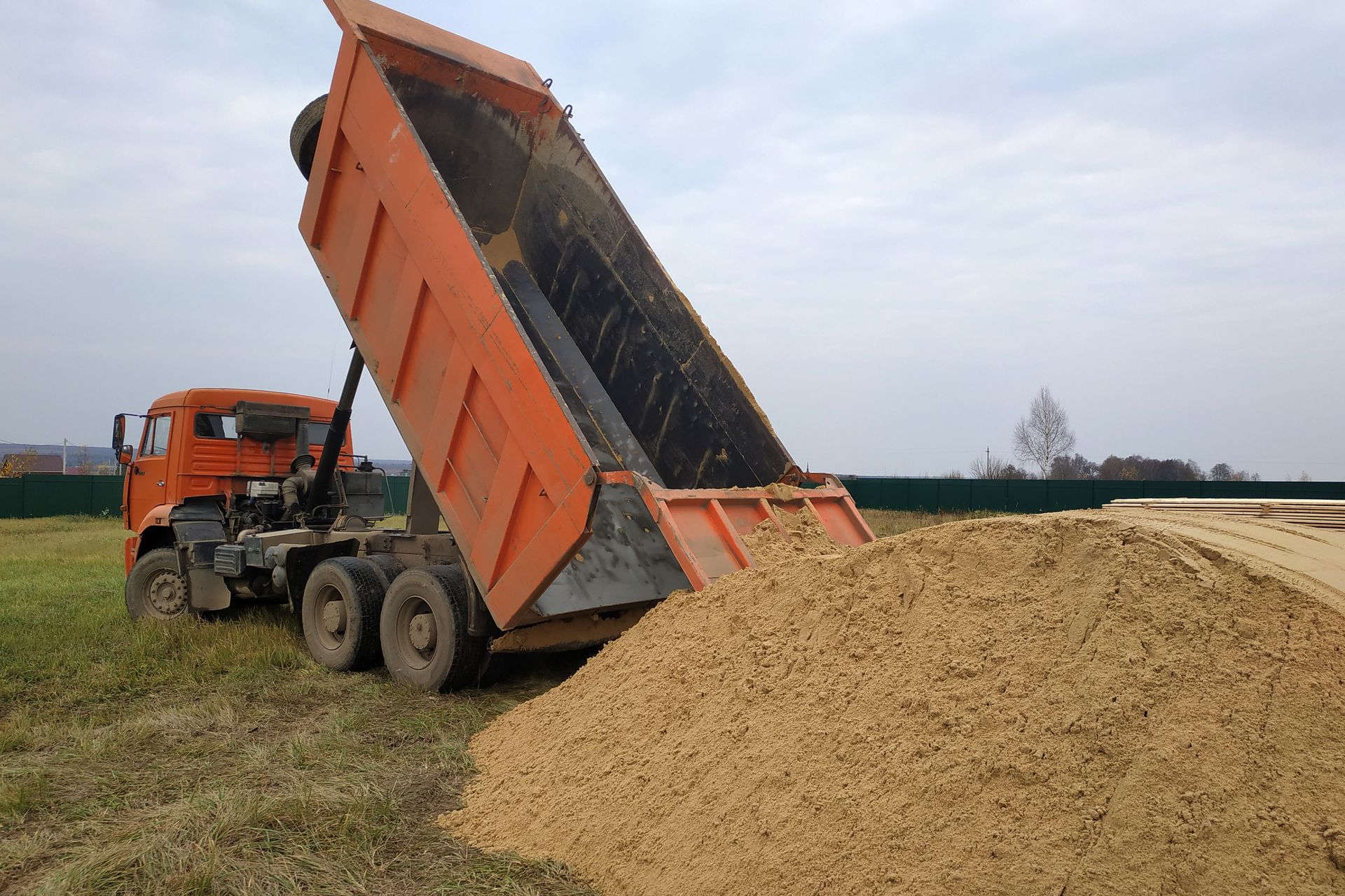 A dump truck is being loaded with dirt in a field.