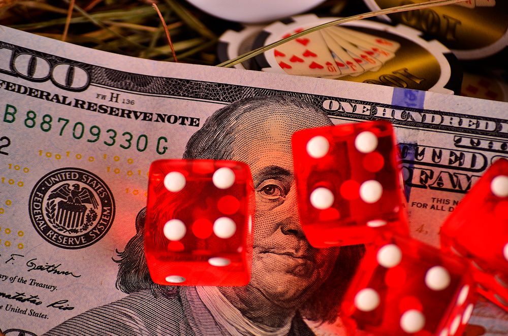 Gambling image of red dice lying on a 100 dollar bill