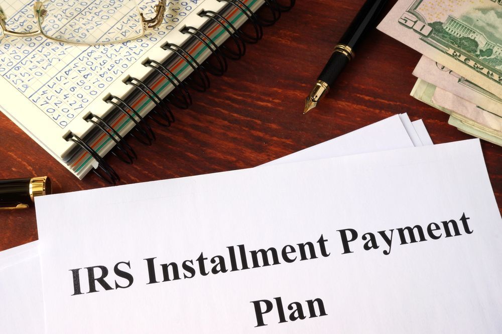 Installment Payment Plan typed on a white paper lying on a desk with money and a notebook