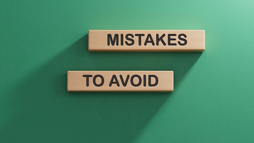 Scrabble words that say MISTAKES TO AVOID lying on a green background