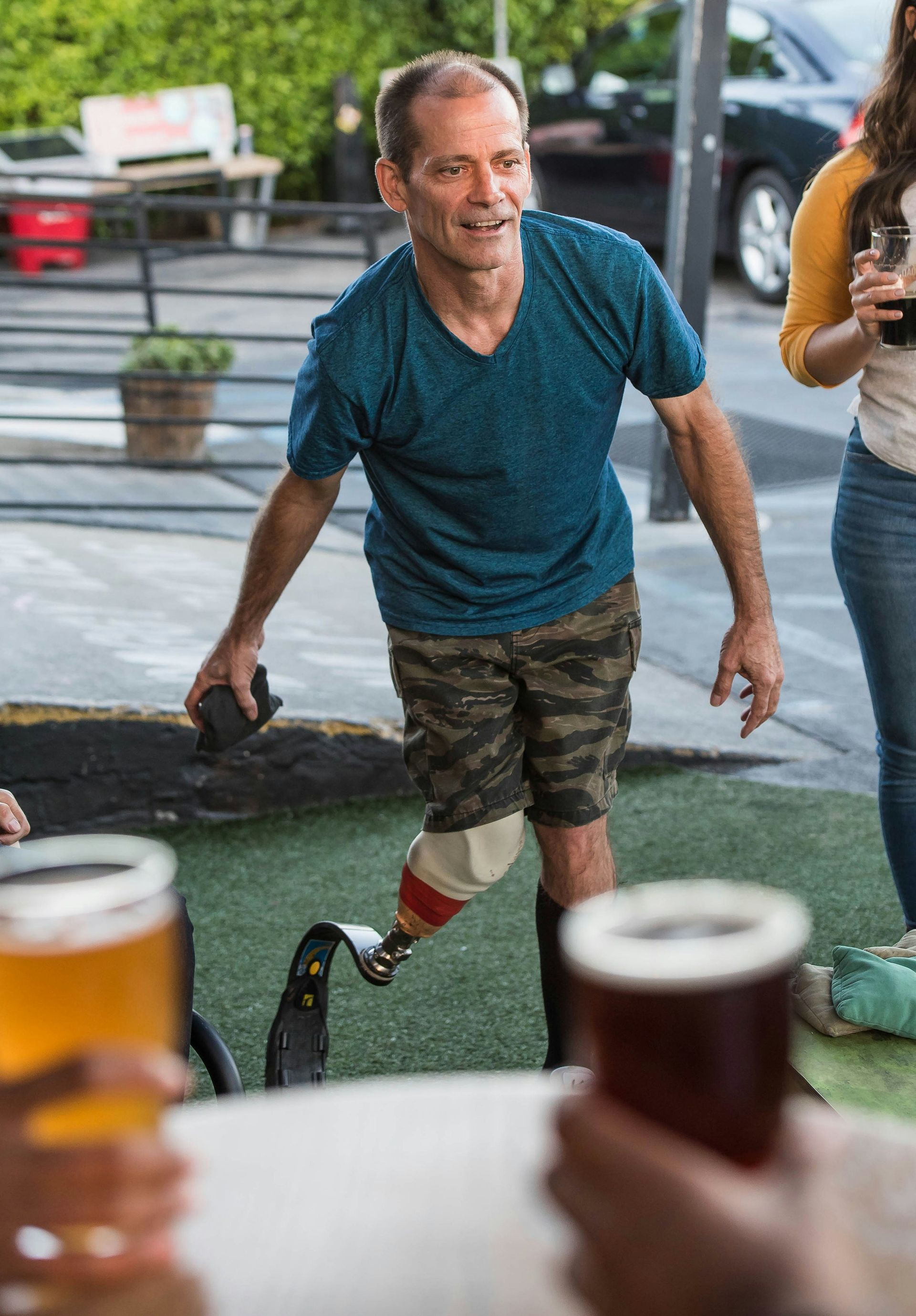A man with a prosthetic leg is standing next to a table with beer.