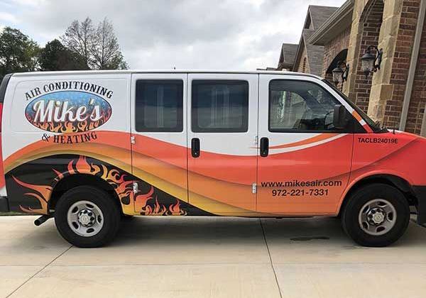 Mike’s Air Conditioning service van, orange and white, parked outside a brick building.
