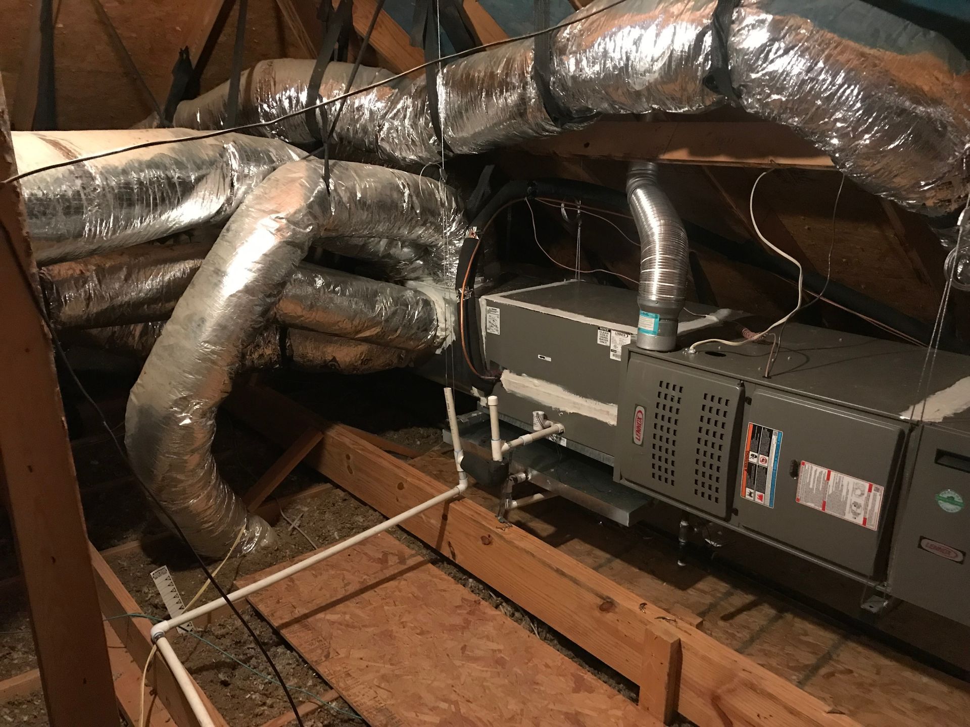 Basement crawlspace with HVAC unit and silver ductwork over exposed wooden framing