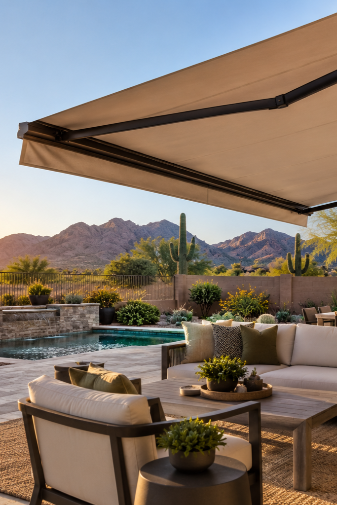 Backyard patio with beige shade sail, cushioned seating, and coffee table in desert setting