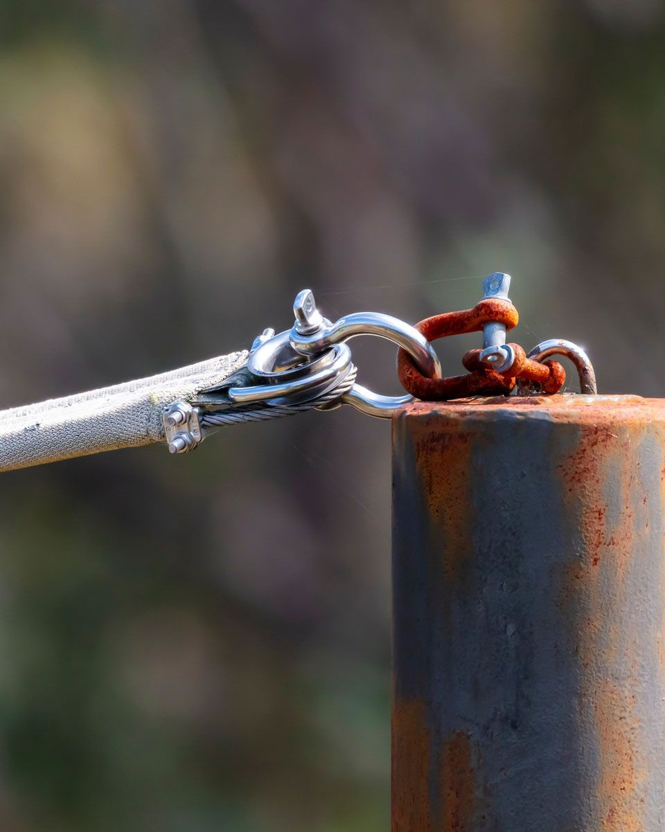 A metal shade sail post with a rusty fitting