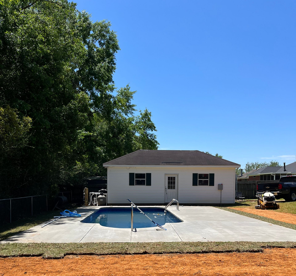 A man is cleaning a swimming pool with a hose.