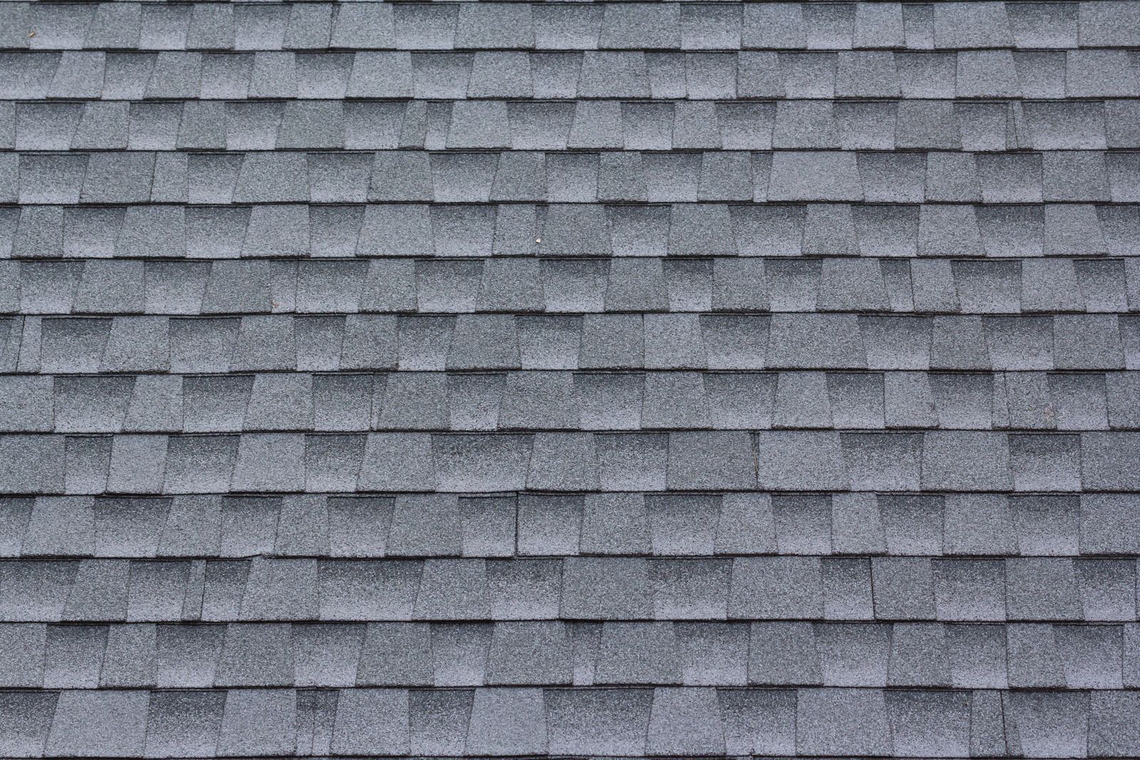 A close-up view of textured gray architectural asphalt roof shingles arranged in overlapping horizontal rows.