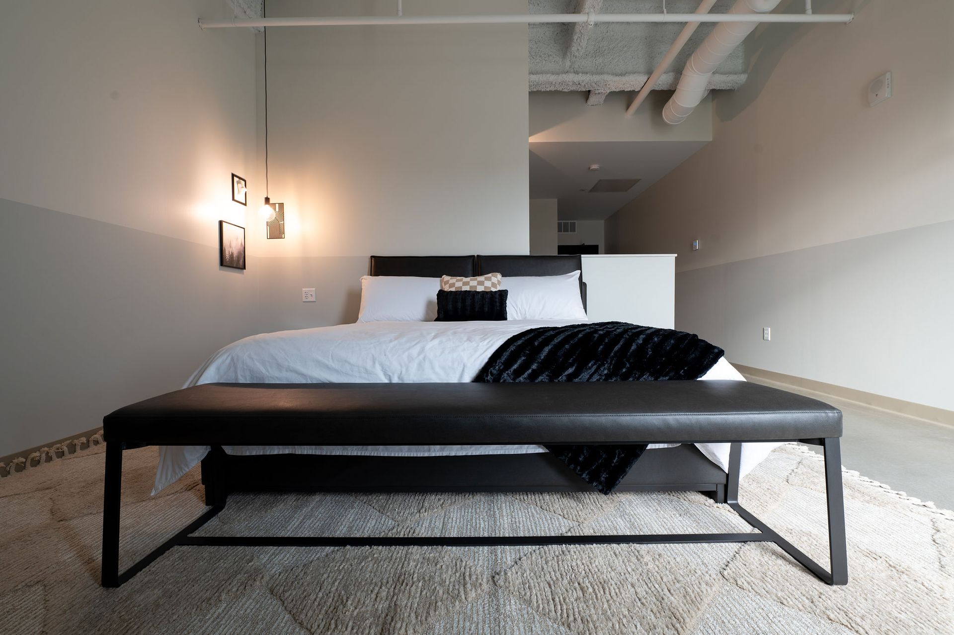 Modern bedroom with a low black bed frame, white bedding, and minimalist decor in a bright room