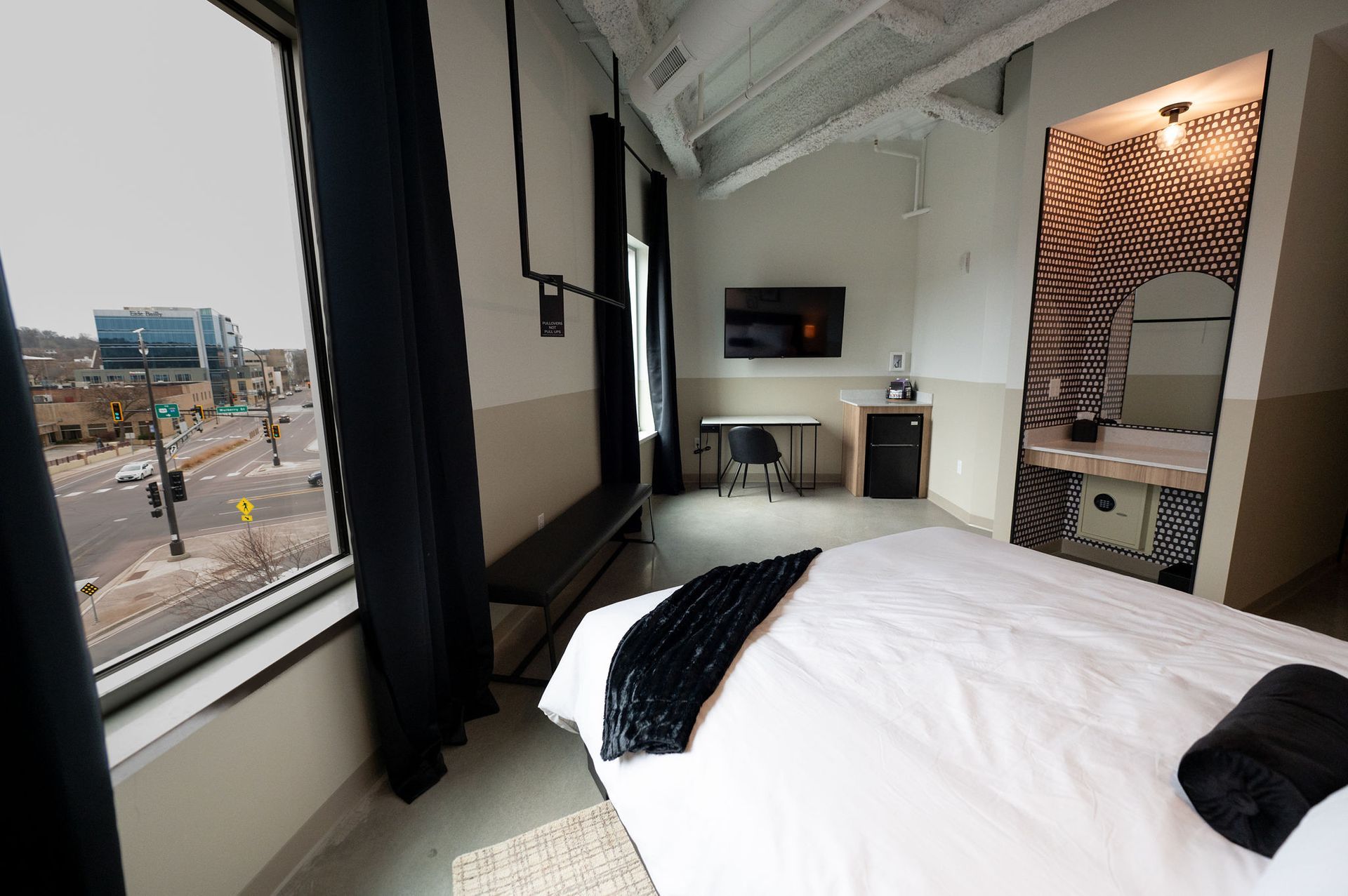 Modern hotel room with a bed, large window, and city view