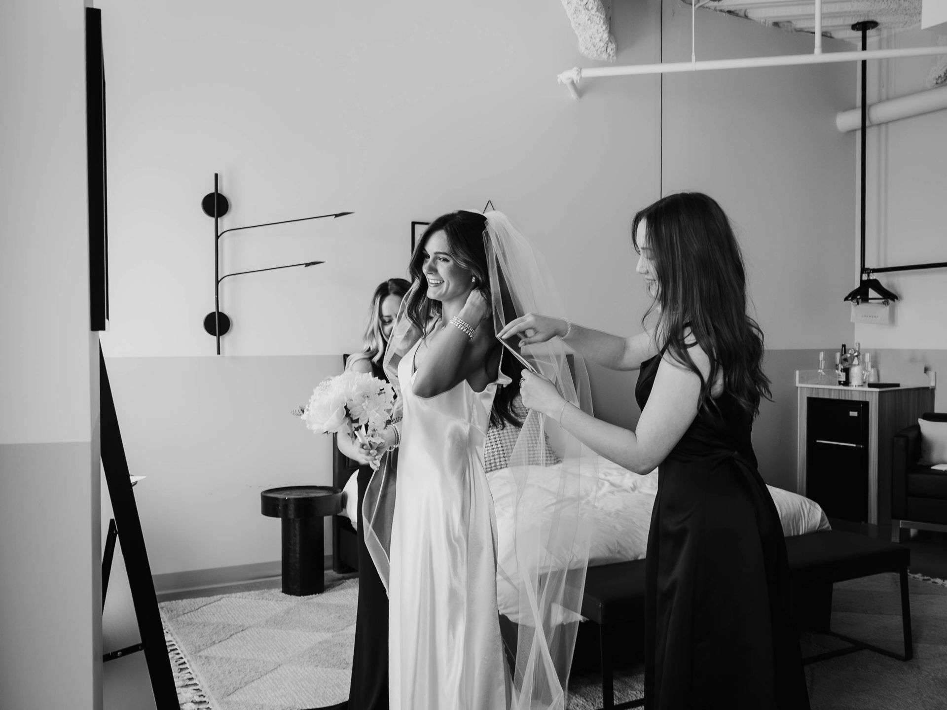Two women adjusting a dress on a model in a boutique fitting room