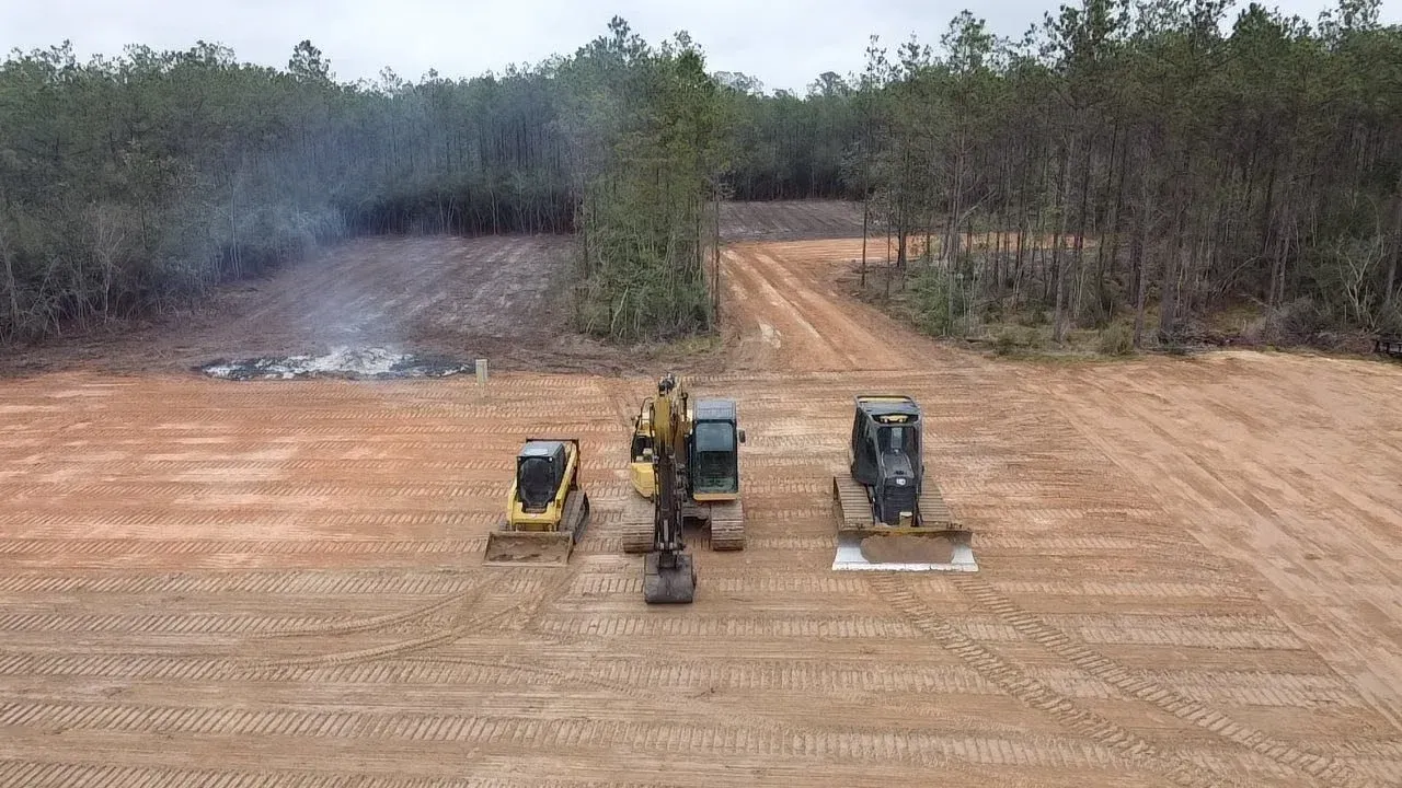 Wet concrete pouring from a truck chute onto a construction site, forming a gravelly slab surface