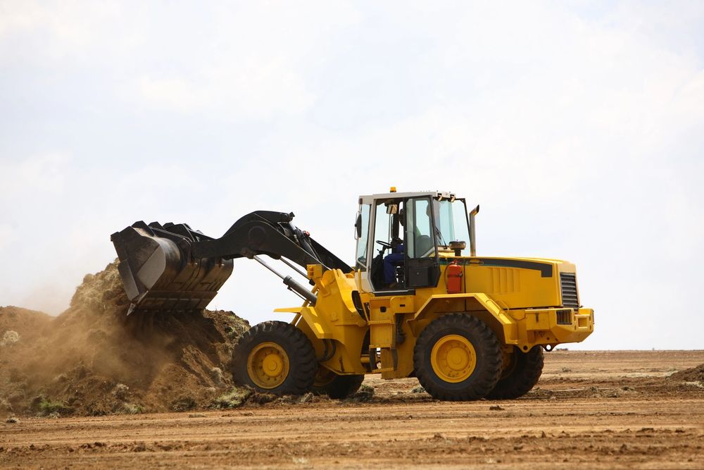 Escavatore in opera durante la modellazione del terreno in un cantiere di movimento terra.