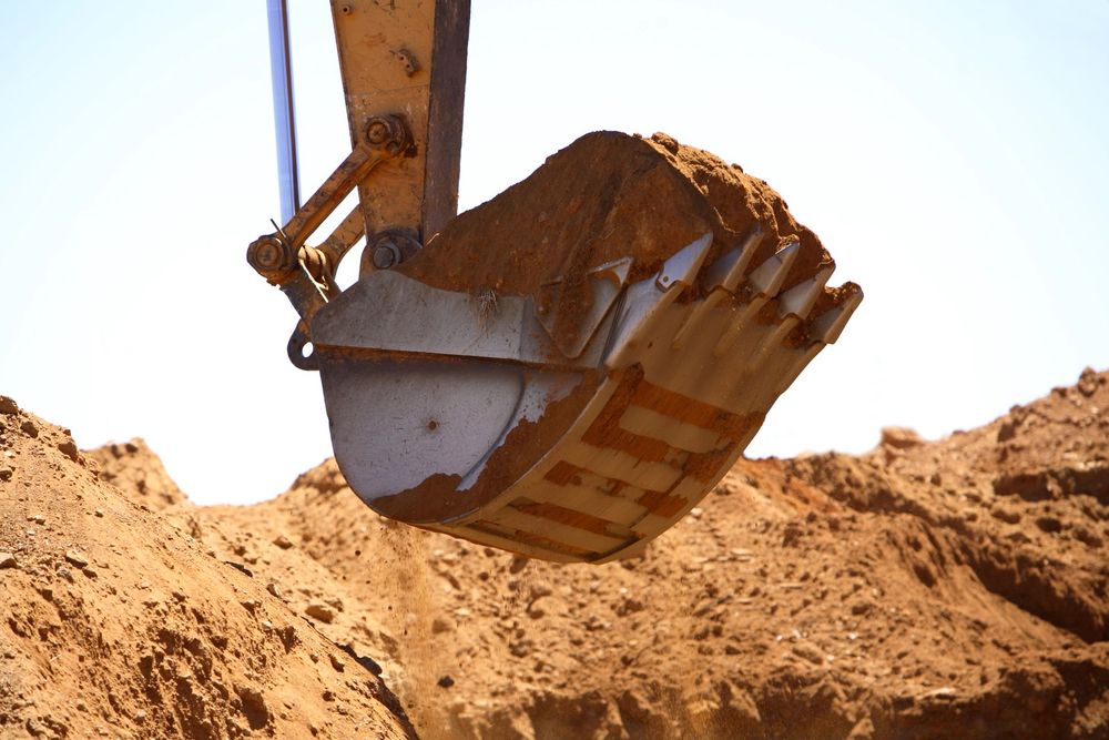 Escavatore in opera durante la modellazione del terreno in un cantiere di movimento terra.