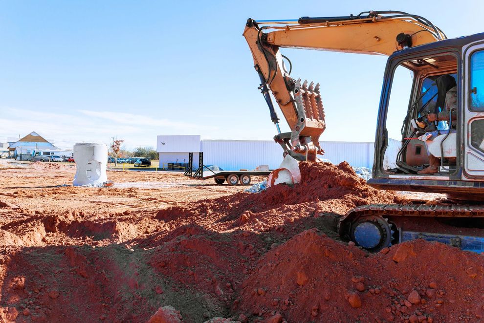 Escavatore al lavoro durante il livellamento del terreno in un cantiere edile.